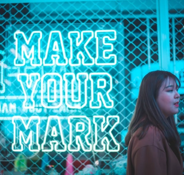 Female PR walking past sign with make your mark written on it